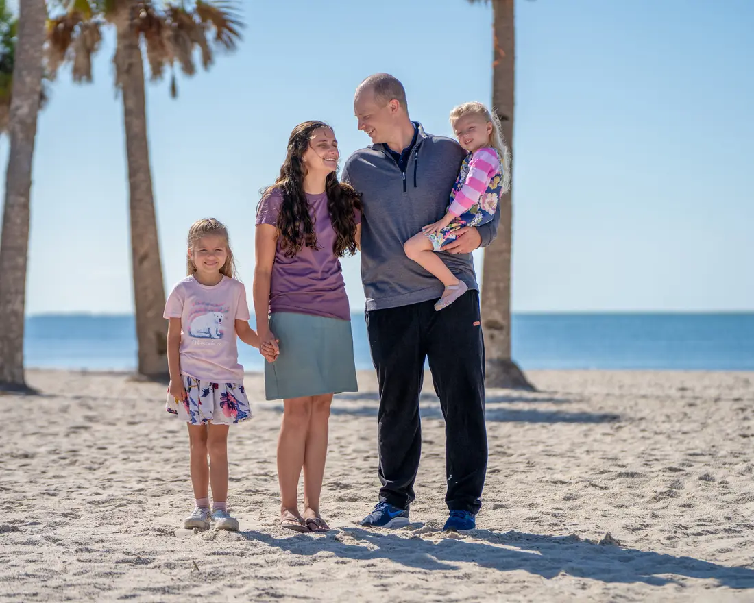 Family on a beach with palm trees behind them